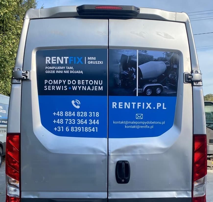 Tył srebrnego busa na wprost: na drzwiach granatowo-niebieskie oklejenie RENTFIX z trzema numerami telefonów, adresem rentfix.pl i adresami e-mail, po bokach pionowe lampy.